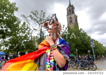 Masked therian girl in colorful rainbow cape poses during CSD celebration in Magdeburg, Germany, with cathedral behind. Scene reflects youth subculture, fandom, identity, pride, creativity, community Masked therian girl in colorful rainbow cape poses during CSD celebration in Magdeburg, Germany, with cathedral behind. Scene reflects youth subculture, fandom, identity, pride, creativity, community 142335722