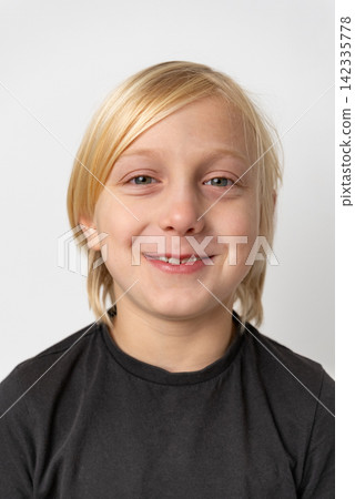 Blond young boy with a cheerful facial expression is smiling confidently at the camera, portraying feelings of joy, childhood, and positive optimism Blond young boy with a cheerful facial expression is smiling confidently at the camera, portraying feelings of joy, childhood, and positive optimism 142335778