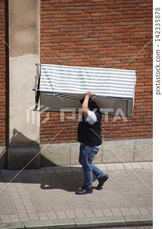 Man carrying a furniture in the street Man carrying a furniture in the street 142335878