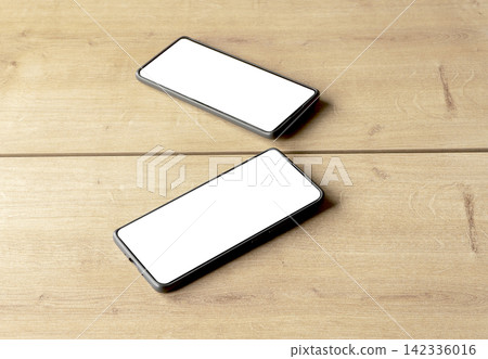 A smartphone with a blank white screen lies at an angle on a wooden table, its mirror reflection A smartphone with a blank white screen lies at an angle on a wooden table, its mirror reflection 142336016