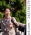 A woman smiles as she answers questions in a street interview. 142336179