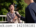 A woman smiles and answers when a microphone is pointed at her. 142336181