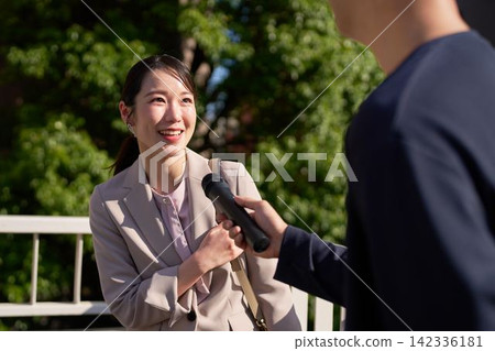 A woman smiles and answers when a microphone is pointed at her. A woman smiles and answers when a microphone is pointed at her. 142336181
