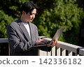 Office worker opening laptop outdoors 142336182