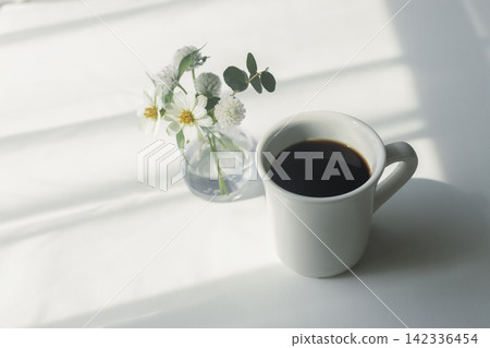 清晨柔和的陽光、白色的花朵和濃鬱的黑咖啡,構成了一幅美麗的畫面。 清晨柔和的陽光、白色的花朵和濃鬱的黑咖啡,構成了一幅美麗的畫面。 142336454