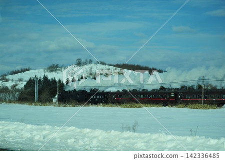 SL冬季沼澤地列車在白雪皚皚的山丘背景下行駛。 SL冬季沼澤地列車在白雪皚皚的山丘背景下行駛。 142336485