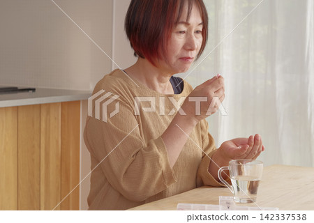 一位老年婦女正在嘗試服用口服藥物。 一位老年婦女正在嘗試服用口服藥物。 142337538