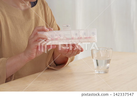 一位女士正在使用藥盒來管理她的藥物。 一位女士正在使用藥盒來管理她的藥物。 142337547