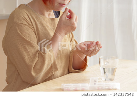 A senior woman trying to take oral medication. A senior woman trying to take oral medication. 142337548
