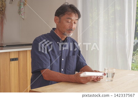 一名男子使用藥盒管理他的藥物。 142337567
