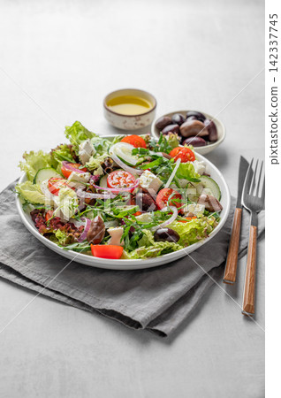 Fresh Greek salad with feta cheese, olives and vegetables in a plate on a light table 142337745