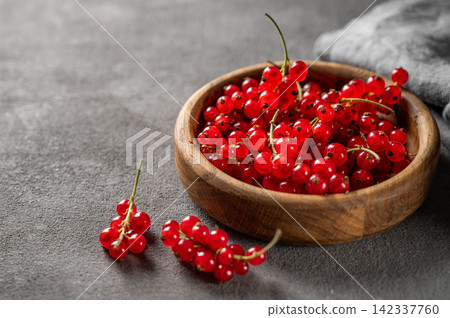 Fresh Red Currants in Wooden Bowl on Dark Textured Background 142337760