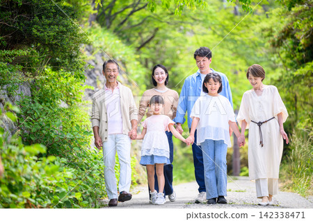 A family of six walks hand in hand through the greenery. A family of six walks hand in hand through the greenery. 142338471