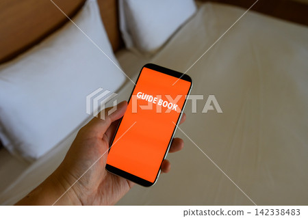 GUIDE BOOK is displayed on the smartphone screen. GUIDE BOOK is displayed on the smartphone screen. 142338483