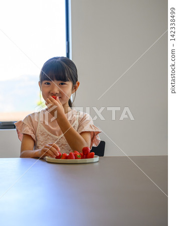 一個女孩在桌子旁吃草莓。 142338499