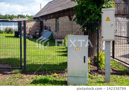 Electrical distribution cabinet outside a building with a fence and lawn Electrical distribution cabinet outside a building with a fence and lawn 142338799