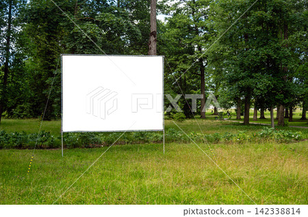 A blank billboard mockup sits in an open field with grass and trees nearby. A blank billboard mockup sits in an open field with grass and trees nearby. 142338814