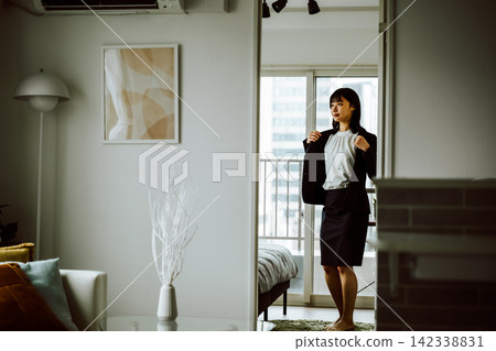 一位身著職業套裝的女商人，一位正在晨間準備的女士。 142338831