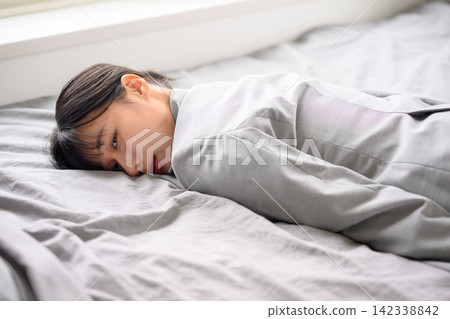 一名身穿西裝的女子疲憊地躺在床上。 142338842