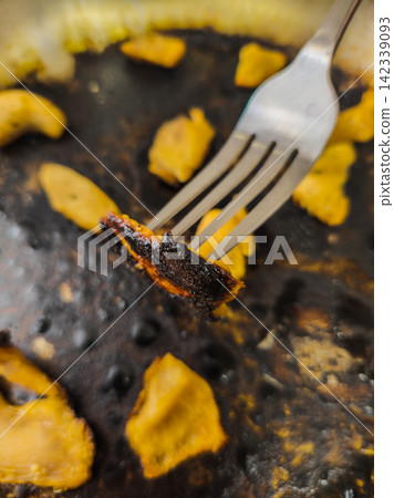 Close-up of Burnt Food on Fork from Greasy Cooking Surface Close-up of Burnt Food on Fork from Greasy Cooking Surface 142339093
