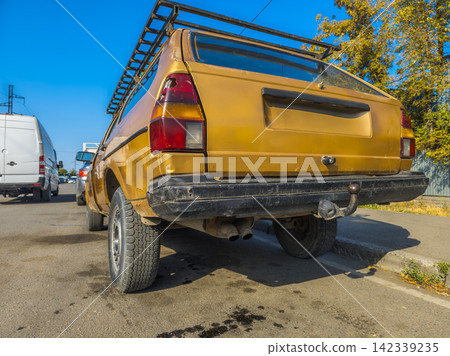 Weathered Gold Station Wagon with Roof Rack on Asphalt Road Weathered Gold Station Wagon with Roof Rack on Asphalt Road 142339235