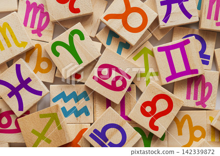 A collection of wooden blocks featuring various zodiac signs in bright colors, scattered across a light surface, highlighting the astrological symbols with distinct designs and playful arrangements A collection of wooden blocks featuring various zodiac signs in bright colors, scattered across a light surface, highlighting the astrological symbols with distinct designs and playful arrangements 142339872