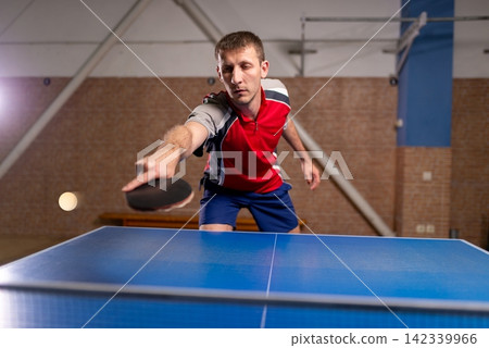 Sportsman striking a ball during a table tennis match Sportsman striking a ball during a table tennis match 142339966