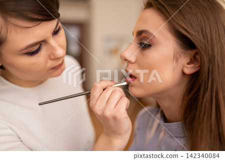 Makeup stylist contouring a model lips with a pink cosmetic pencil Makeup stylist contouring a model lips with a pink cosmetic pencil 142340084