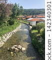 Scenic landscape of a clean mountain river stream flowing past traditional residential houses in Hausham, Upper Bavaria, Germany. 142340301
