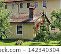 Architectural exterior view of an old traditional building yellow facade featuring an ancient brick chimney pipe in Hausham, Upper Bavaria, Germany. 142340304