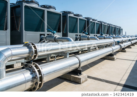 Industrial HVAC units and large pipes on a rooftop under a clear blue sky Industrial HVAC units and large pipes on a rooftop under a clear blue sky 142341419