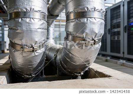 Industrial insulated pipes with metal clamps in a facility setting Industrial insulated pipes with metal clamps in a facility setting 142341438