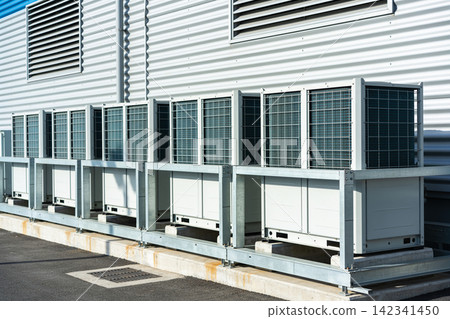 Industrial air conditioning units lined up outside a modern building facade Industrial air conditioning units lined up outside a modern building facade 142341450