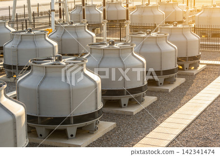 Industrial cooling towers lined up in a row at a power plant during sunset Industrial cooling towers lined up in a row at a power plant during sunset 142341474