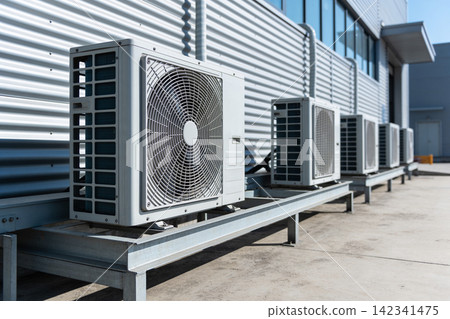Outdoor air conditioning units lined up on a metal platform against a building Outdoor air conditioning units lined up on a metal platform against a building 142341475