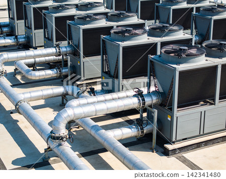Industrial HVAC units with large metal pipes on a rooftop under bright sunlight Industrial HVAC units with large metal pipes on a rooftop under bright sunlight 142341480