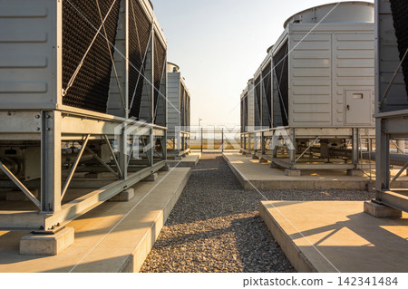 Industrial cooling towers lined up on a sunny day with clear skies above Industrial cooling towers lined up on a sunny day with clear skies above 142341484
