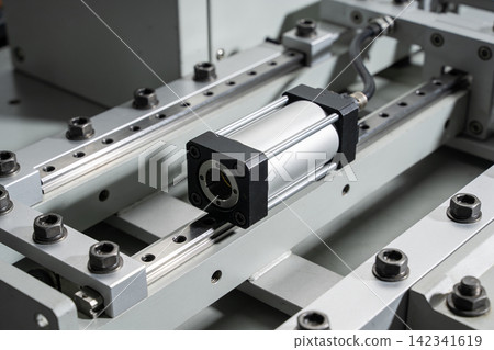 Close-up view of a pneumatic cylinder mounted on linear rails in industrial machinery Close-up view of a pneumatic cylinder mounted on linear rails in industrial machinery 142341619