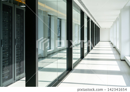Modern data center hallway with server racks and glass walls casting shadows Modern data center hallway with server racks and glass walls casting shadows 142341654