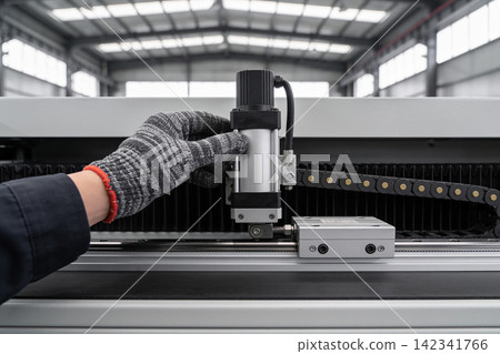 Worker in protective glove adjusts industrial machine component in a factory setting Worker in protective glove adjusts industrial machine component in a factory setting 142341766