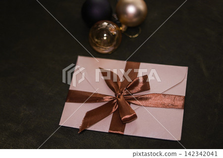 Pink envelope with bronze ribbon and bow on dark background Pink envelope with bronze ribbon and bow on dark background 142342041