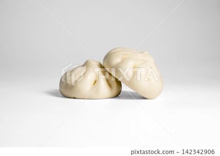 Soft steamed bao buns with pleated tops on bright background Soft steamed bao buns with pleated tops on bright background 142342906