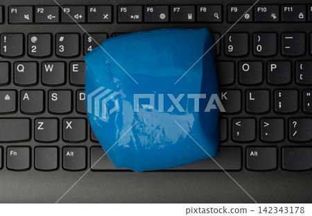 Blue slime placed on a black laptop keyboard in a home office Blue slime placed on a black laptop keyboard in a home office 142343178