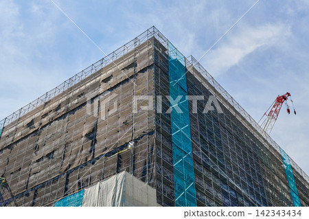 正在興建中的高層建築外觀,以及一台直插藍天的大型起重機。 正在興建中的高層建築外觀,以及一台直插藍天的大型起重機。 142343434