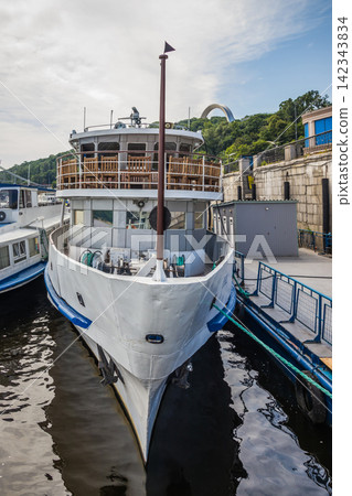 River ship at the pier. River pleasure boat moored in the port awaiting boarding of passengers. Walks on holidays and weekends. River ship at the pier. River pleasure boat moored in the port awaiting boarding of passengers. Walks on holidays and weekends. 142343834