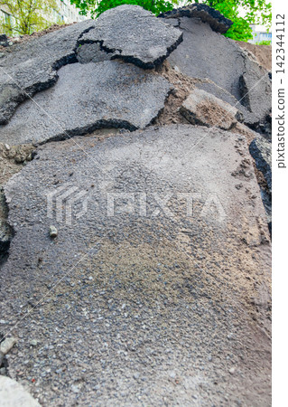 A pile of broken asphalt near a hole with broken pipes in the courtyard of an old house A pile of broken asphalt near a hole with broken pipes in the courtyard of an old house 142344112