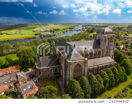 High angle wide horizontal aerial drone photograph of Grote Kerk church, historic houses, canal locks, polder landscape, and dramatic storm sky in Veere, Zeeland, Netherlands on sunny summer day High angle wide horizontal aerial drone photograph of Grote Kerk church, historic houses, canal locks, polder landscape, and dramatic storm sky in Veere, Zeeland, Netherlands on sunny summer day 142344387