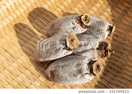 將乾柿子(koro-gaki)塗上白色粉末,放在篩子上;柿霜;十二月 將乾柿子(koro-gaki)塗上白色粉末,放在篩子上;柿霜;十二月 142344823