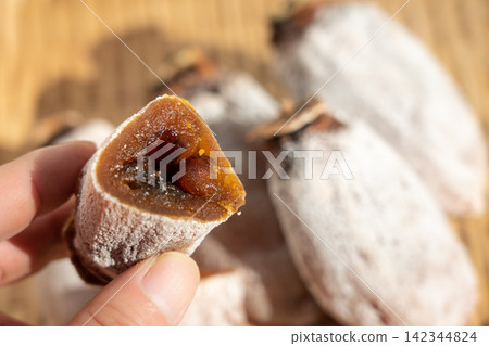 A dried persimmon (koro-gaki) covered in white powder, placed on a sieve, and another dried persimmon cut in half. (Persimmon frost, December) A dried persimmon (koro-gaki) covered in white powder, placed on a sieve, and another dried persimmon cut in half. (Persimmon frost, December) 142344824