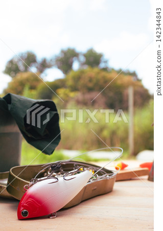 Fishing lure resting on a tackle box, preparing for an exciting day of angling, symbolizing outdoor hobbies, leisure activity, and the pursuit of sport fish in nature Fishing lure resting on a tackle box, preparing for an exciting day of angling, symbolizing outdoor hobbies, leisure activity, and the pursuit of sport fish in nature 142344843